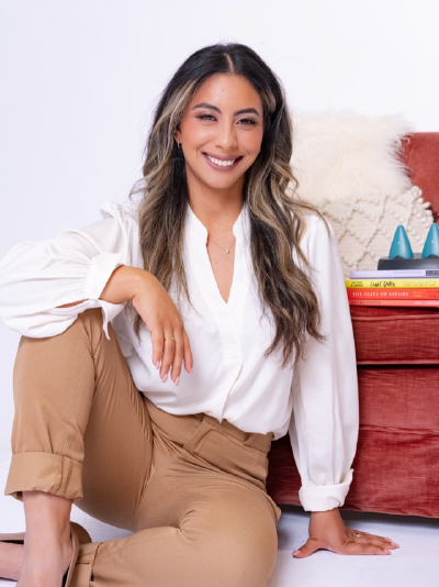 Brunette woman sitting on the floor in front of a chair.