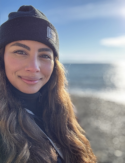 Brunette woman with a beach in the background.
